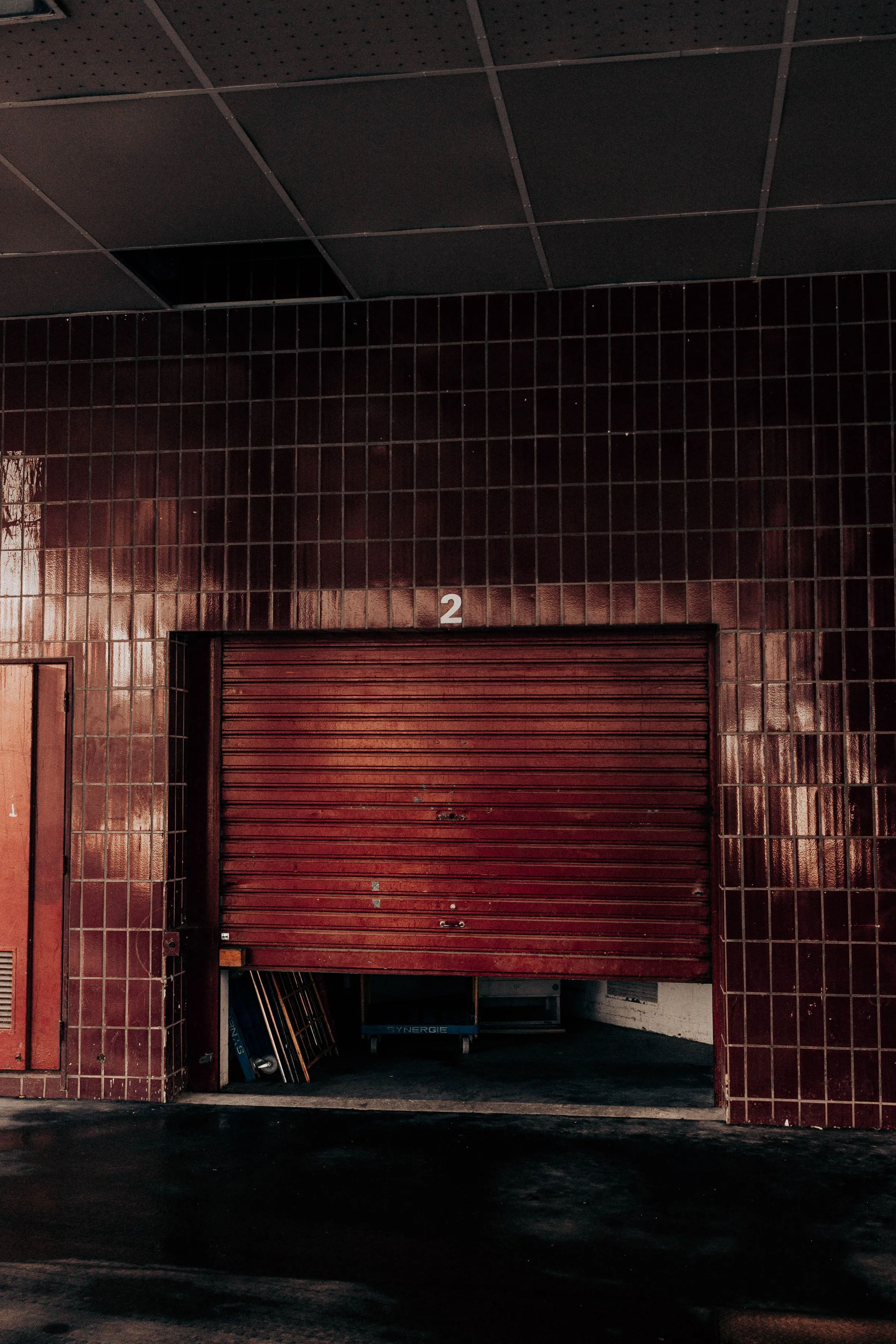 Half-open metal rolling garage door at a parking entrance