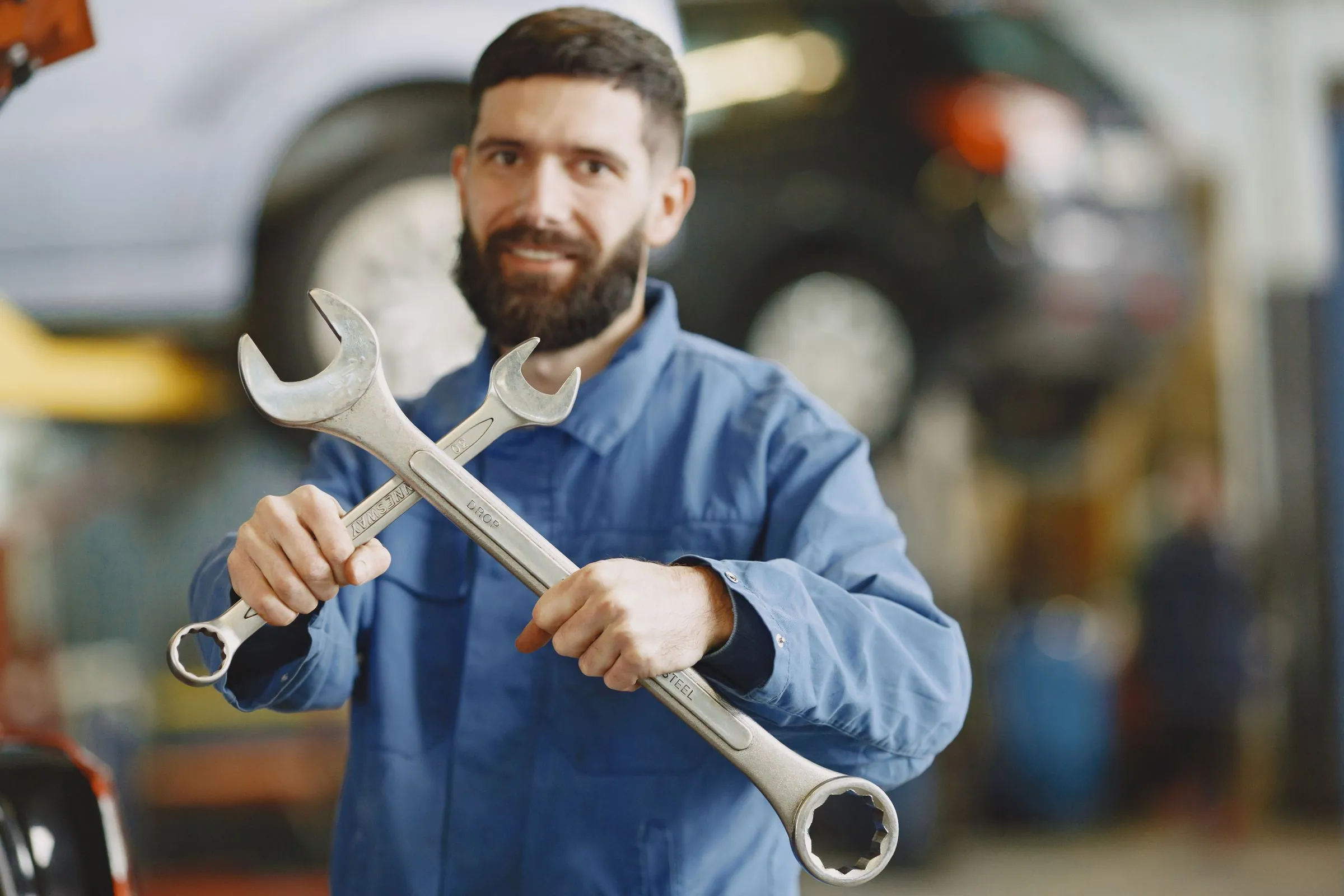 Technician in a blue uniform holding wrenches before a service call
